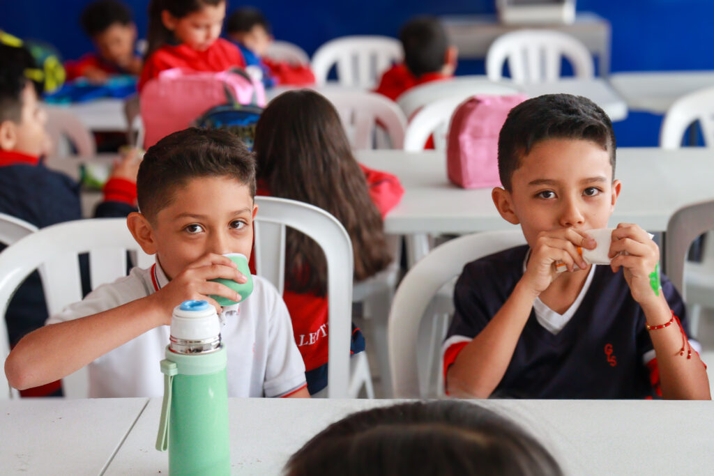 Dos estudiantes sentados en el restaurante bebiendo de un termo verde